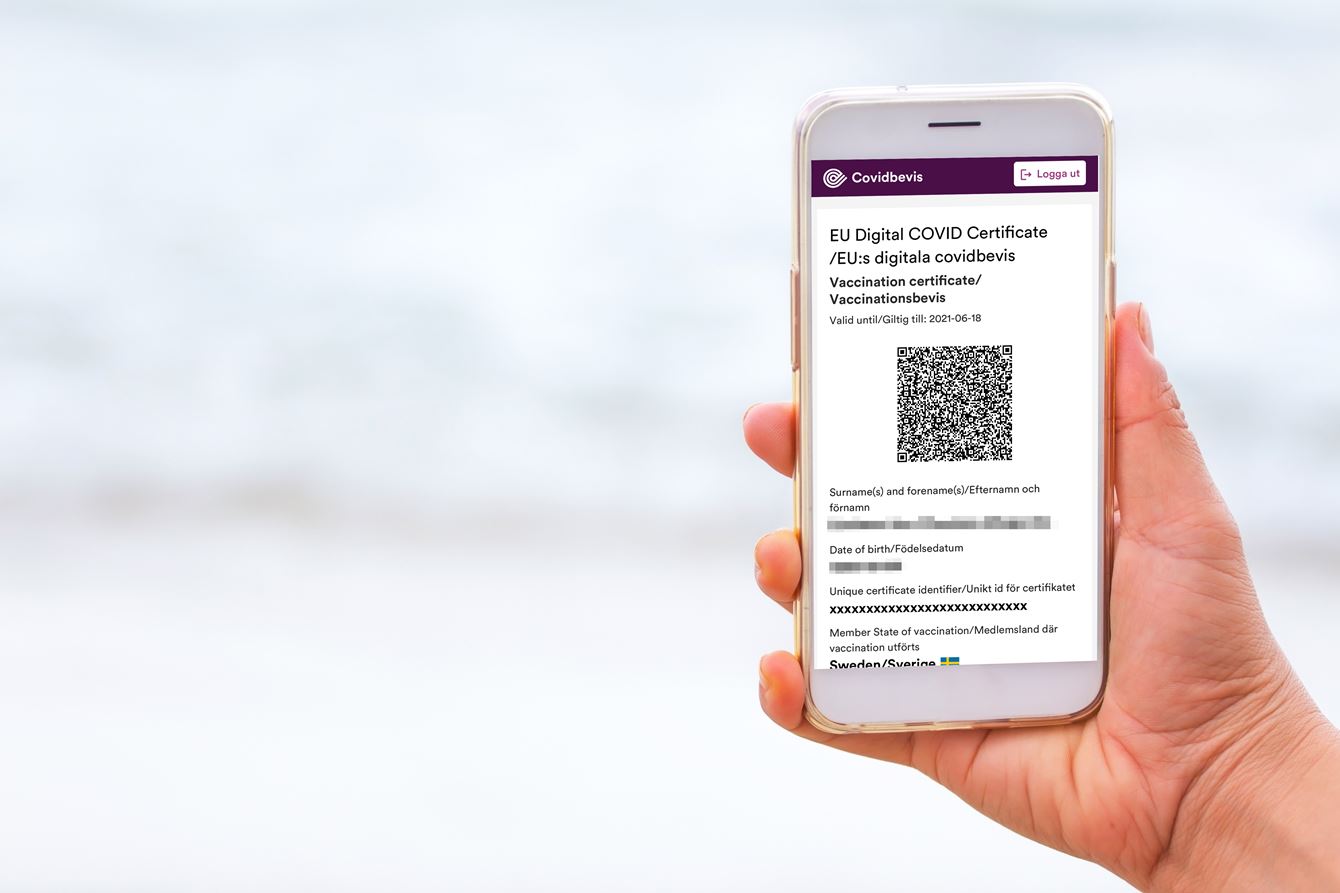 Hand som håller i en telefon som visar ett covidbevis