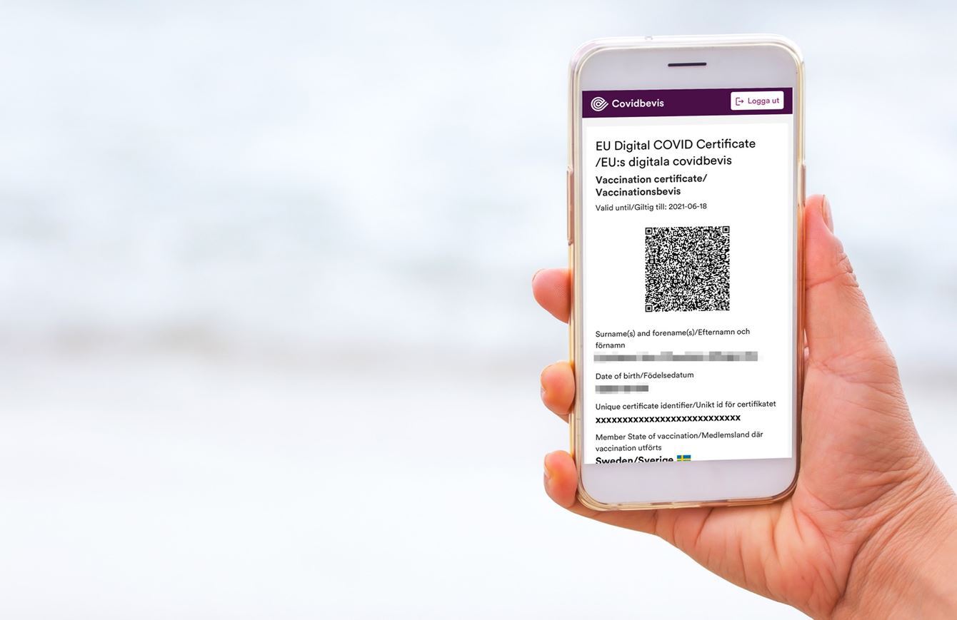 En hand håller en mobiltelefon som visar ett covidbevis.