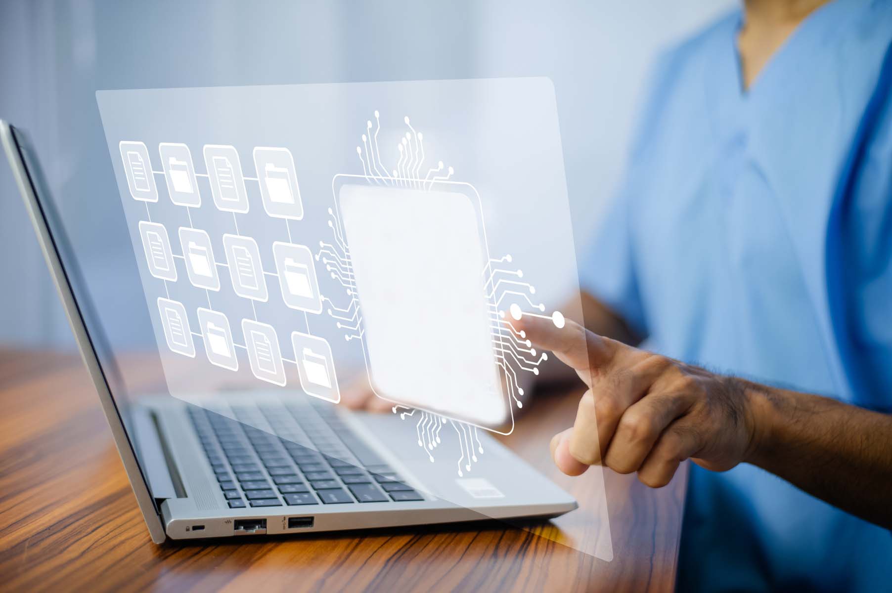 Läkare sitter vid laptop, beredd att använda tangentbordet. Ansiktet syns inte.